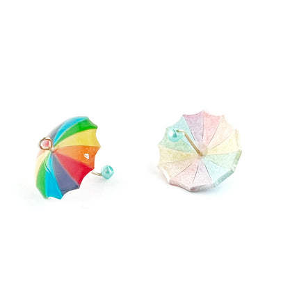 A pair of miniature umbrella-shaped earrings on a plain white background. One earring is shown from the front, featuring a vibrant, multi-colored rainbow design with green, yellow, orange, red, and blue segments.
