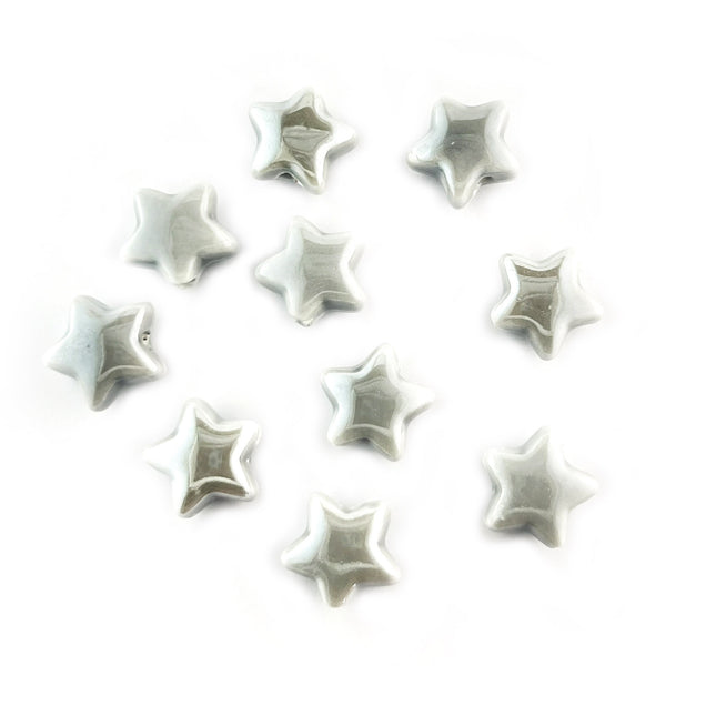 Ten small glossy star-shaped ceramic beads in a light gray color, arranged on a plain white background.