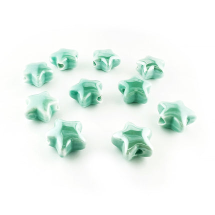 Ten small glossy star-shaped ceramic beads in a light mint green color, arranged on a plain white background.