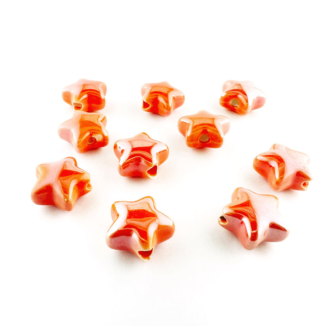 Ten glossy ceramic, five-pointed star-shaped beads in a orange lustre finish, arranged on a plain white background.