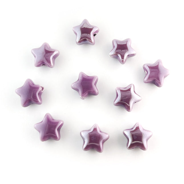 Ten small lavender ceramic star-shaped beads arranged on a plain white background.
