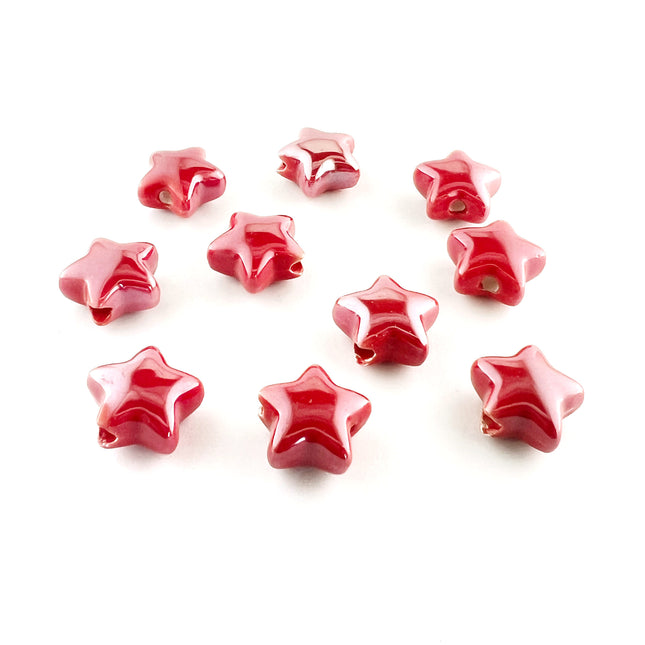 Ten glossy red ceramic star-shaped beads with a lustre finish, arranged on a plain white background.