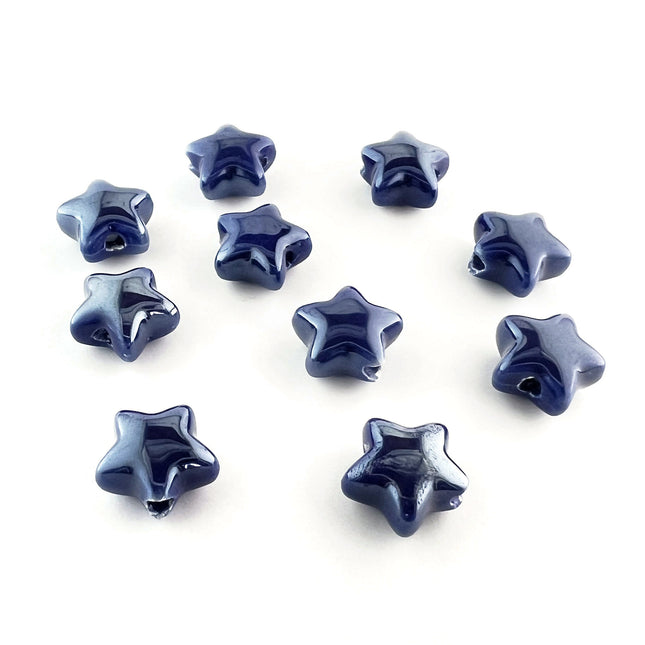 Ten glossy dark blue ceramic star-shaped beads arranged on a plain white background.