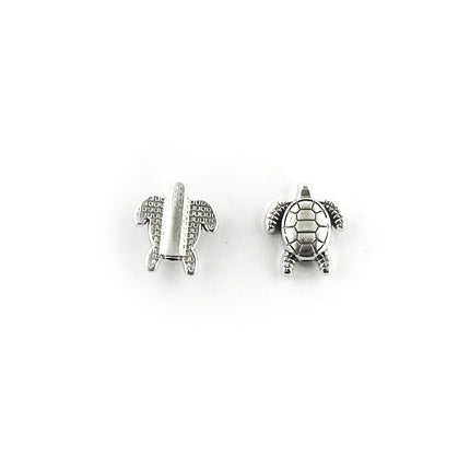 Two small silver sea turtle jewellery beads, one showing the back and the other showing the top with a textured shell, on a plain white background.