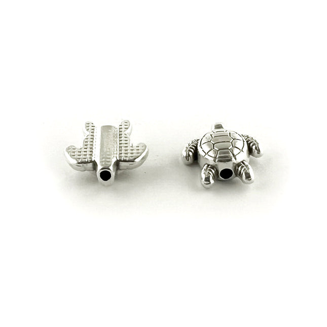 Two small silver-toned metal beads, shaped like a turtle, one is showing the top and the other the underneath of teh bead, shown on a plain white background.