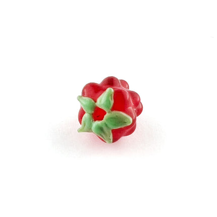 A small red berry charm with green leaves, photographed on a plain white background.