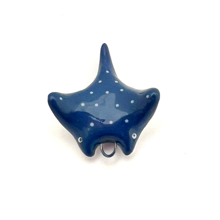 A glossy dark blue stingray pendant with small white polka dots and tiny white eyes, shown on a plain white background.