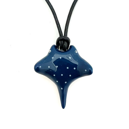 A dark blue starfish-shaped pendant necklace with white polka dots, suspended on a black cord against a plain white background.