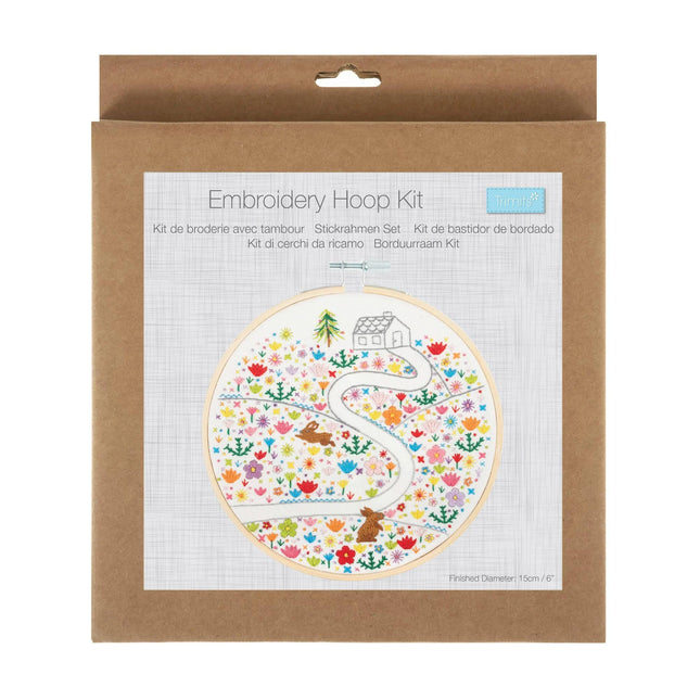 embroidery hoop kit with a path leading up to a house with fields of flowers and plants surrounding the path